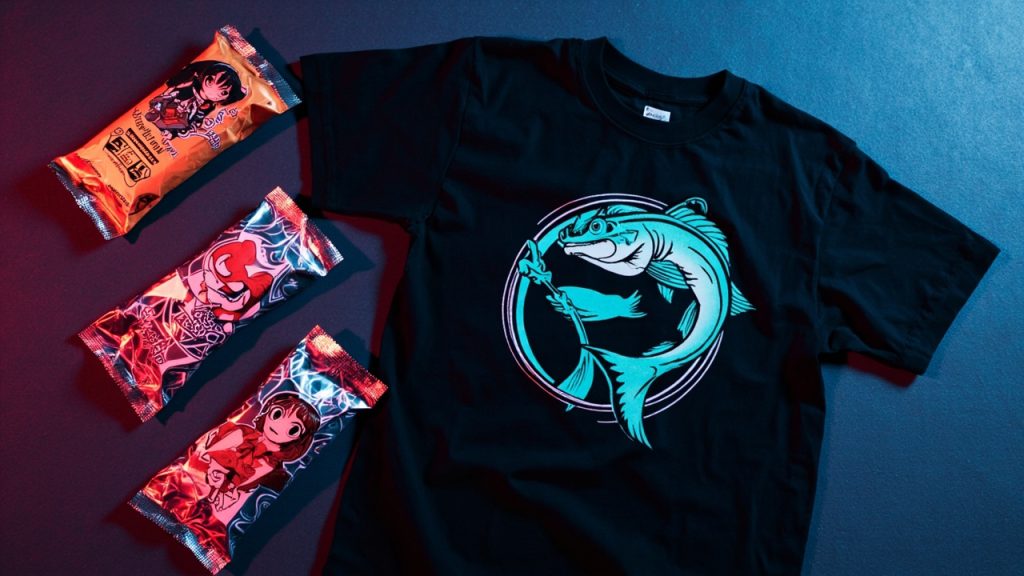 Illustration: Three foil-wrapped packages with character illustrations are displayed alongside a black t-shirt featuring a fish character design, all sharing a retro anime-inspired aesthetic.